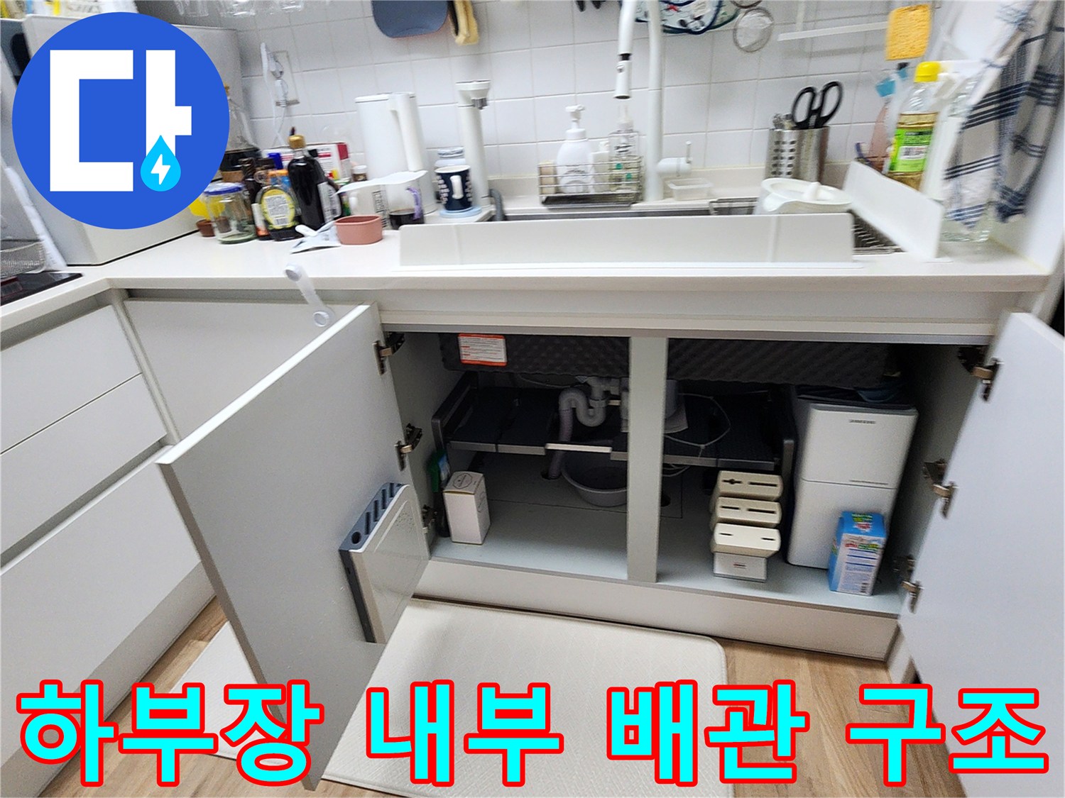 열려있는-싱크대-하부장-안쪽의-배관-설비