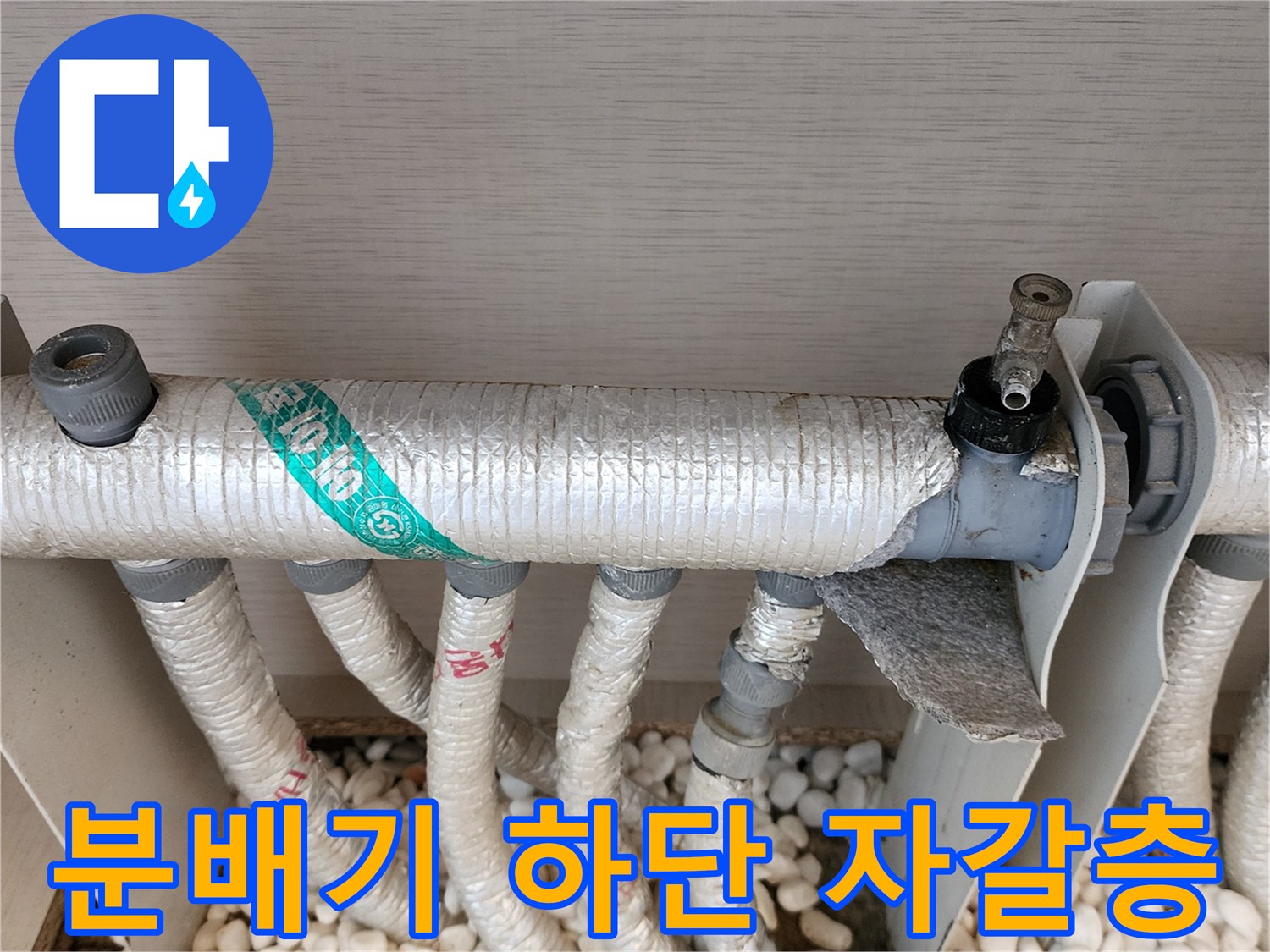 분배기 아래 자갈이 깔린 공간의 배관 연결 상태 사진