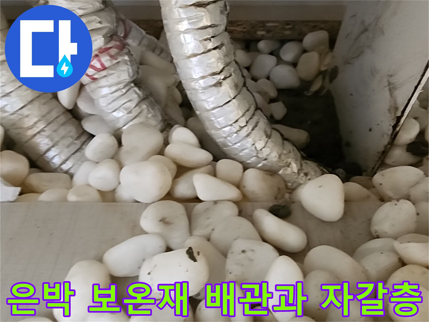 자갈로 채워진 바닥면의 은색 배관 구조