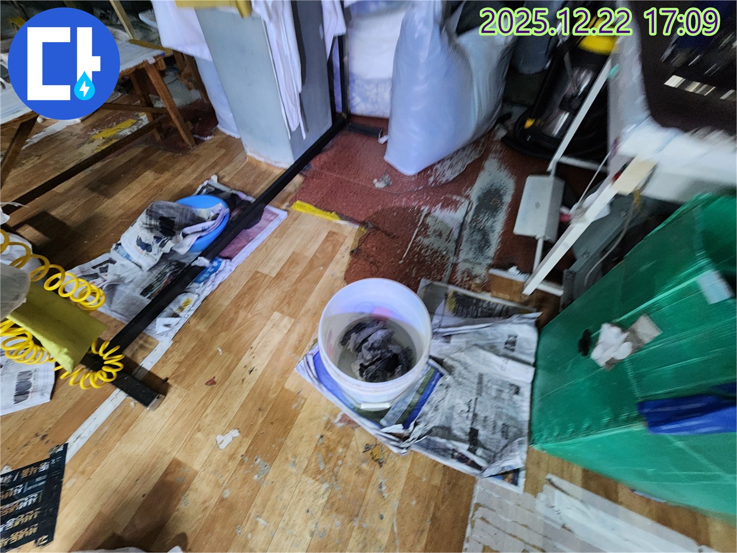누수 피해 흔적 - 바닥에 흥건한 물과 젖은 신문지