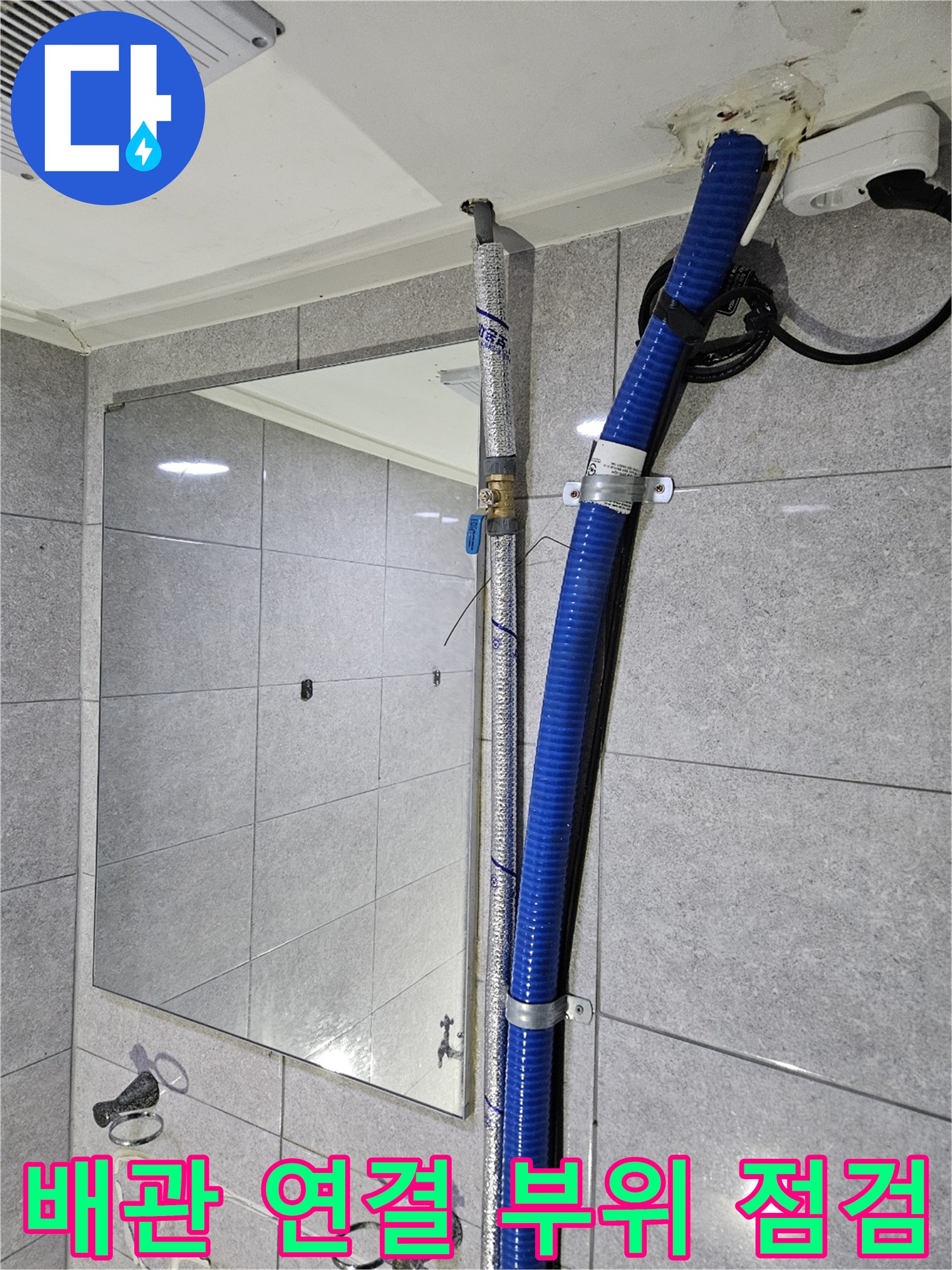 벽면 타일과 인접한 파란색 주름관 배관의 연결부 상세 사진