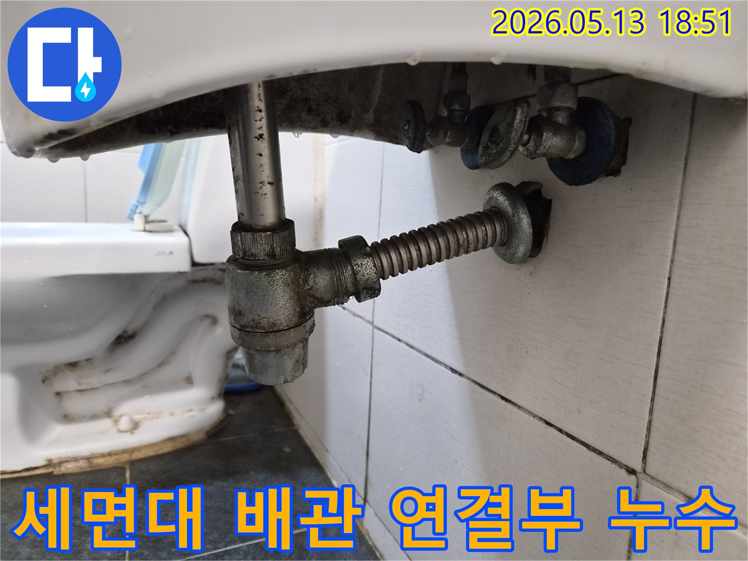 세면대 하부 배관 연결 부위에서 물이 새어 나와-주변에 물방울이 맺힌 모습을 보여줍니다