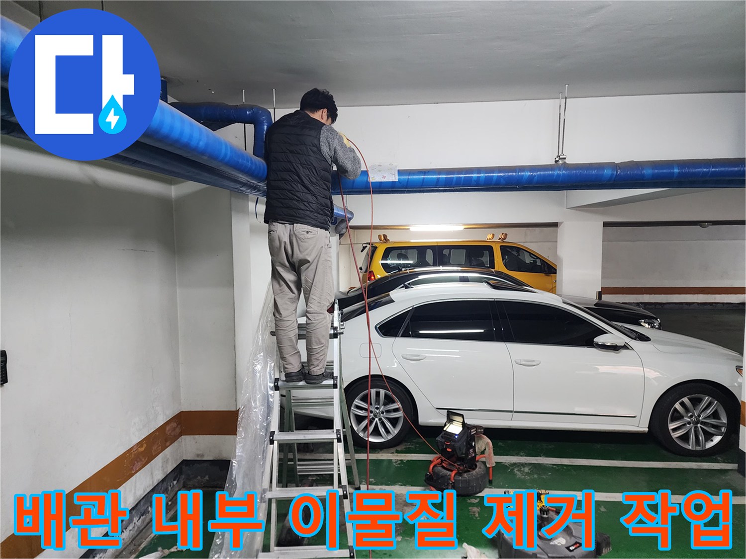 파란색 대형 배관에 고압 세척 장비를 연결하여 작업하는 모습