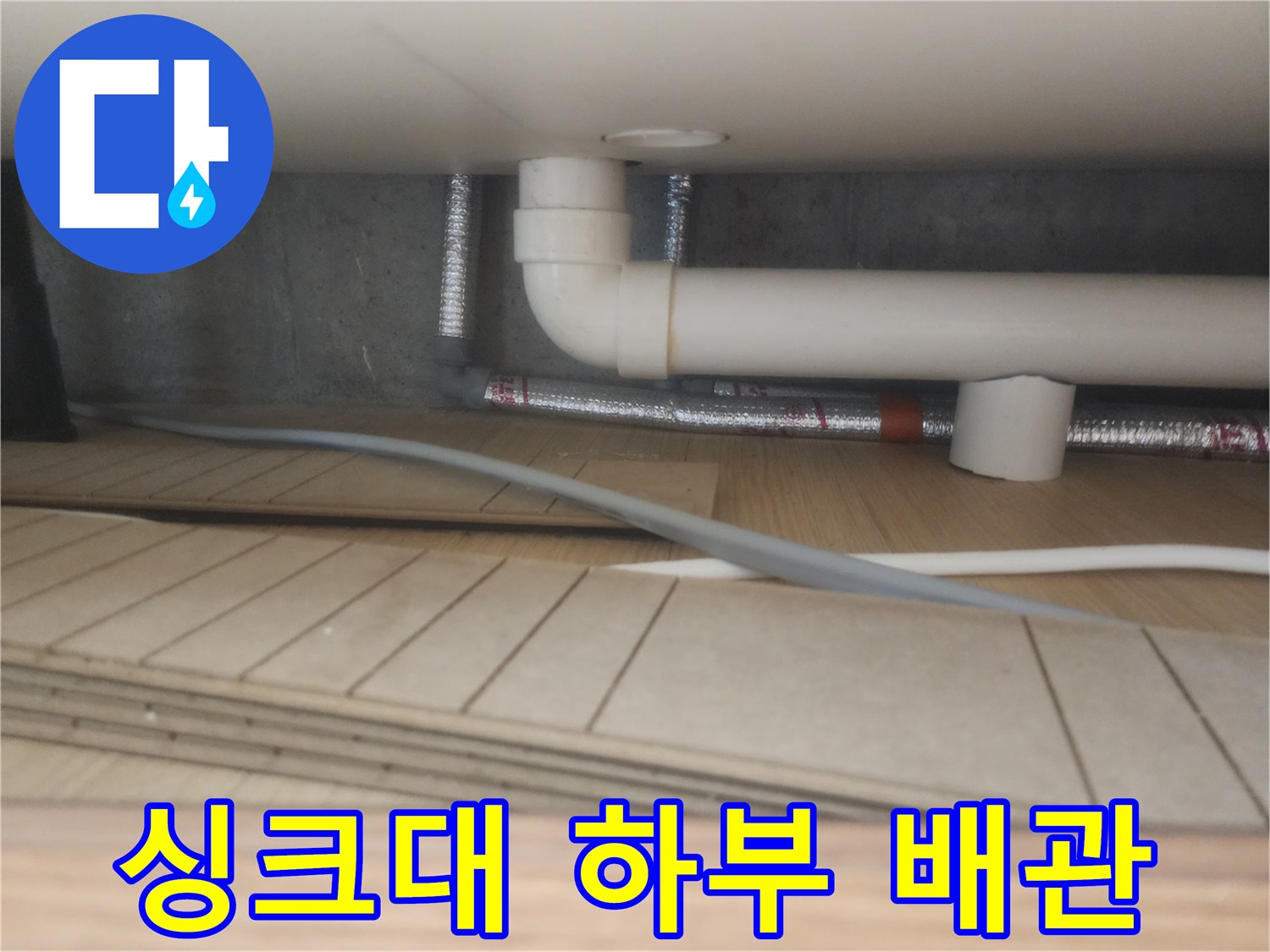 싱크대 아래 흰색 PVC 관과 은색 자재 구성