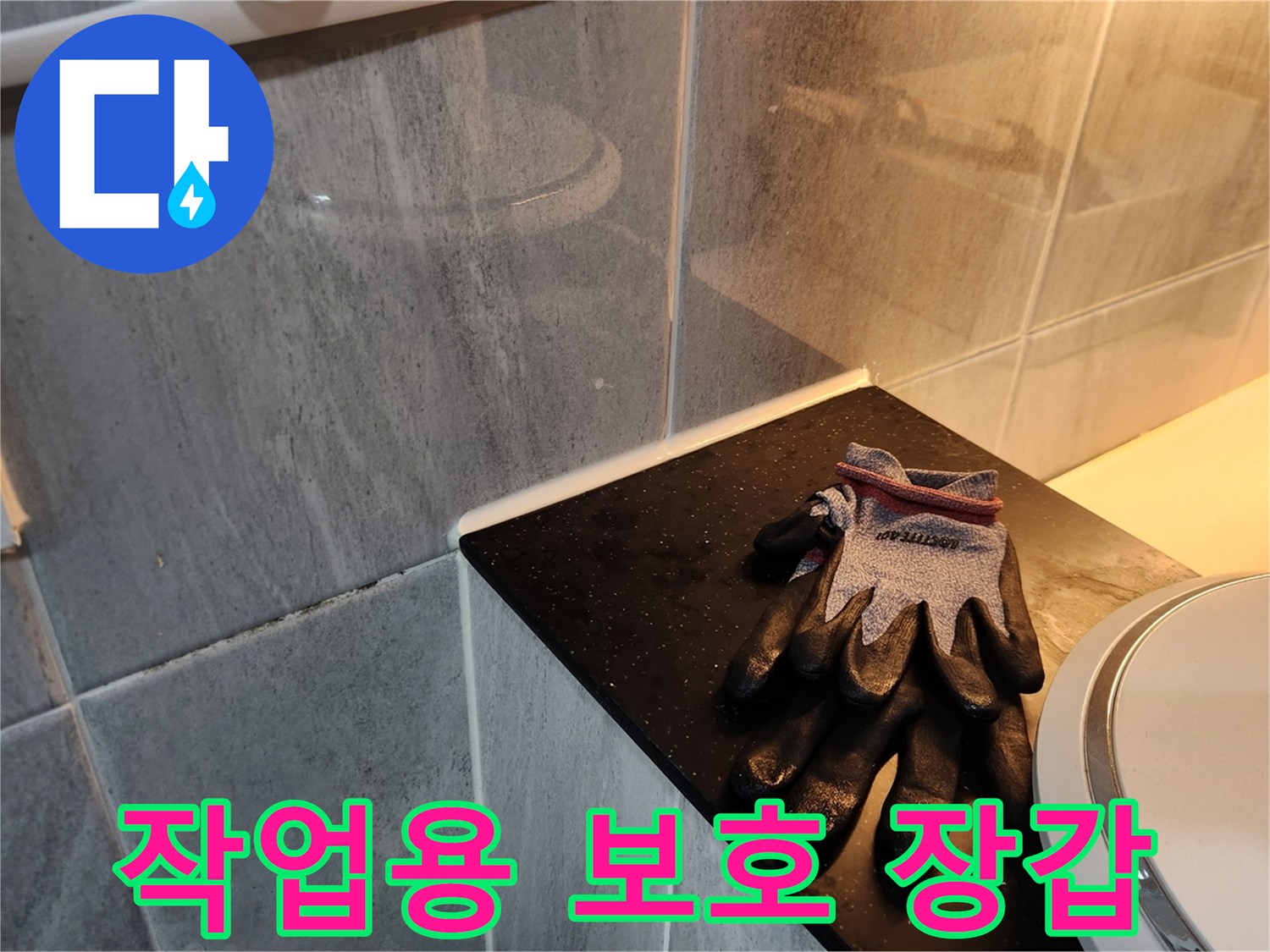 세면대 하단 타일 근처의 작업 장갑