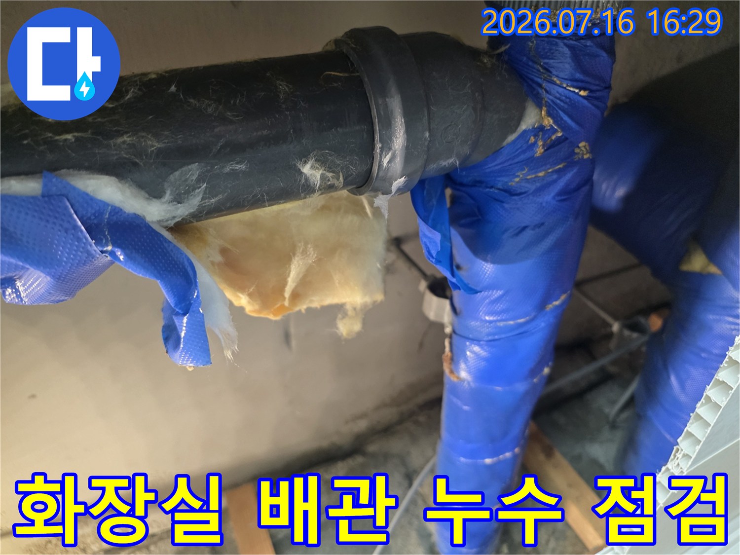 파란색 보온재로 감싸진 화장실 천장 내 배관 연결 부위 점검 모습