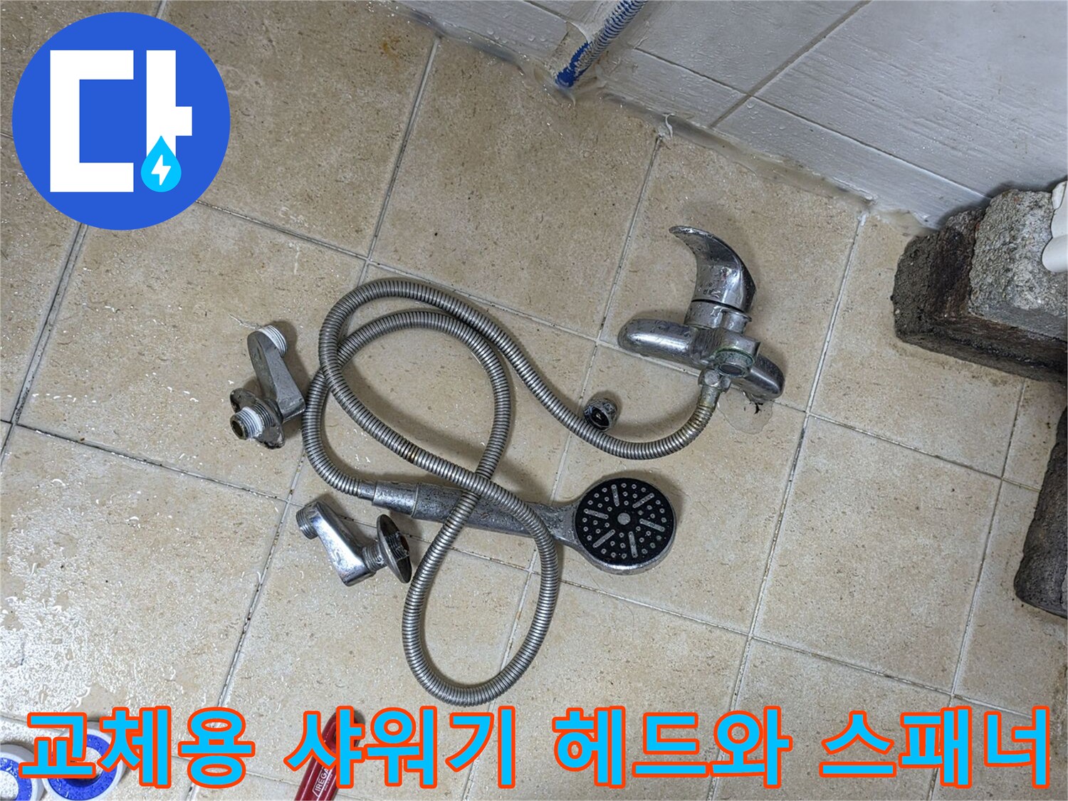 바닥 타일 위에 놓인 작업 도구 및 샤워기 부품