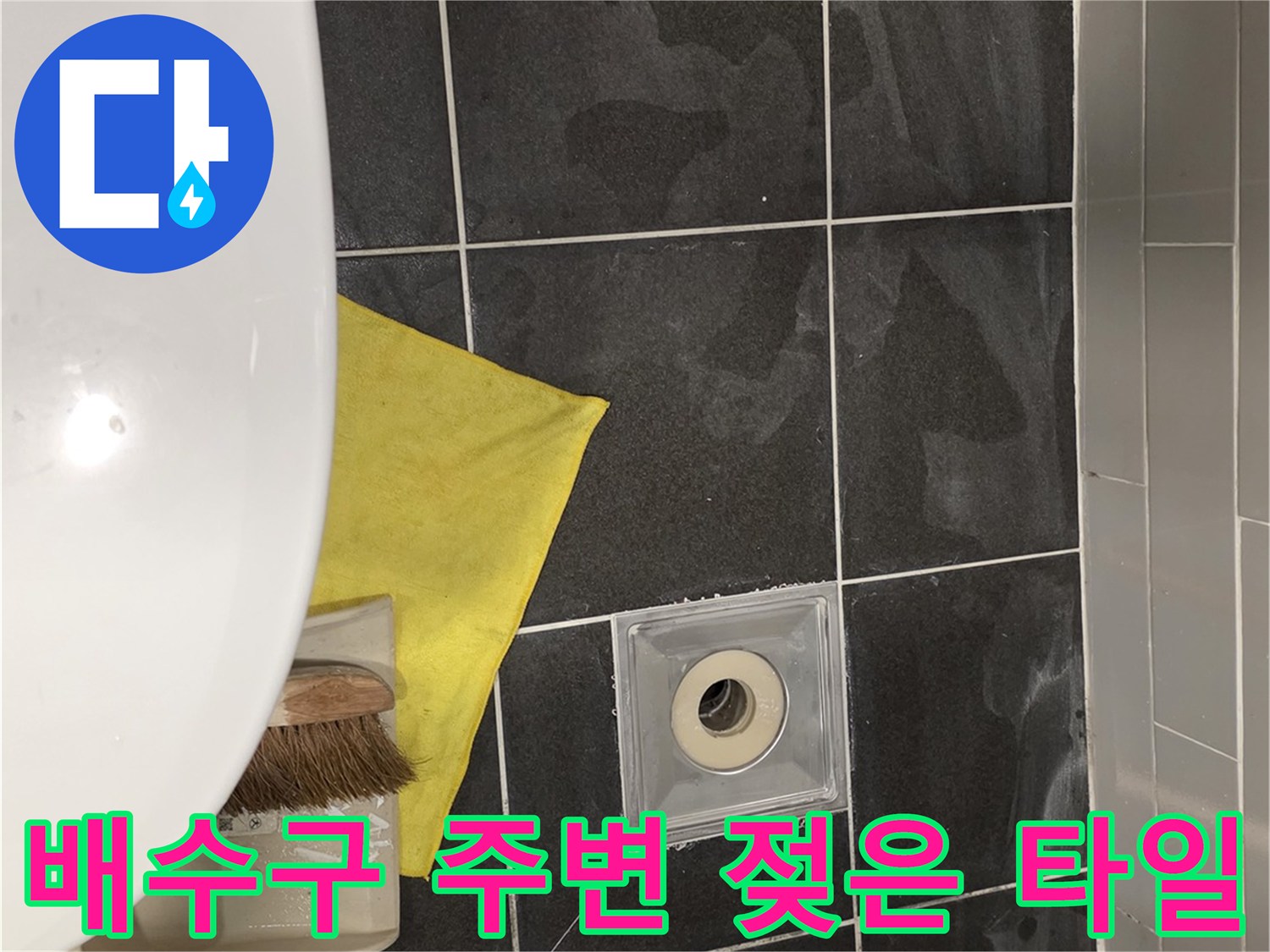 어두운 회색 타일 위 배수구와 습기 흔적
