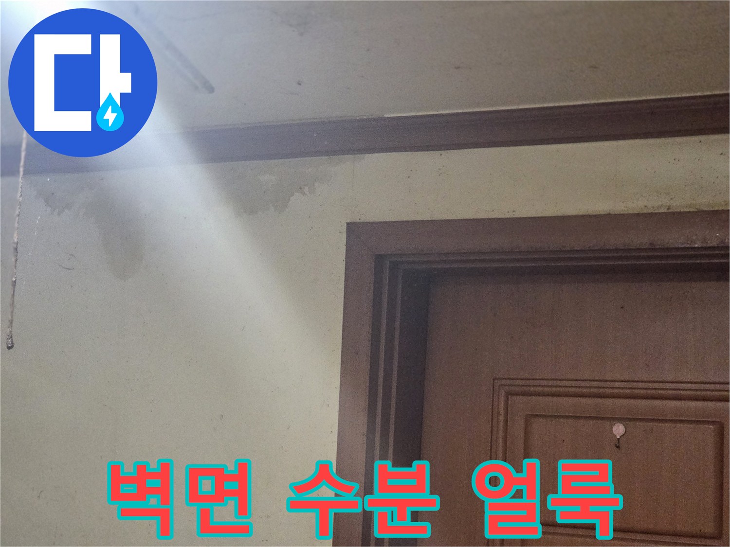문틀 상부 벽지의 젖은 변색 부위