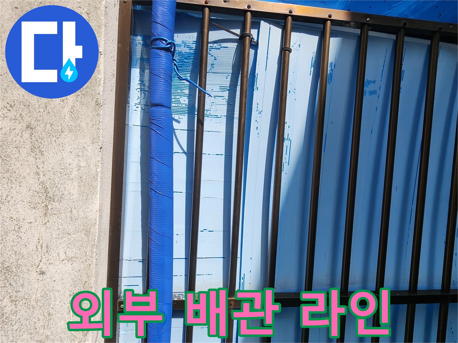 창살 구조물 아래로 지나가는 파란색 배관입니다.