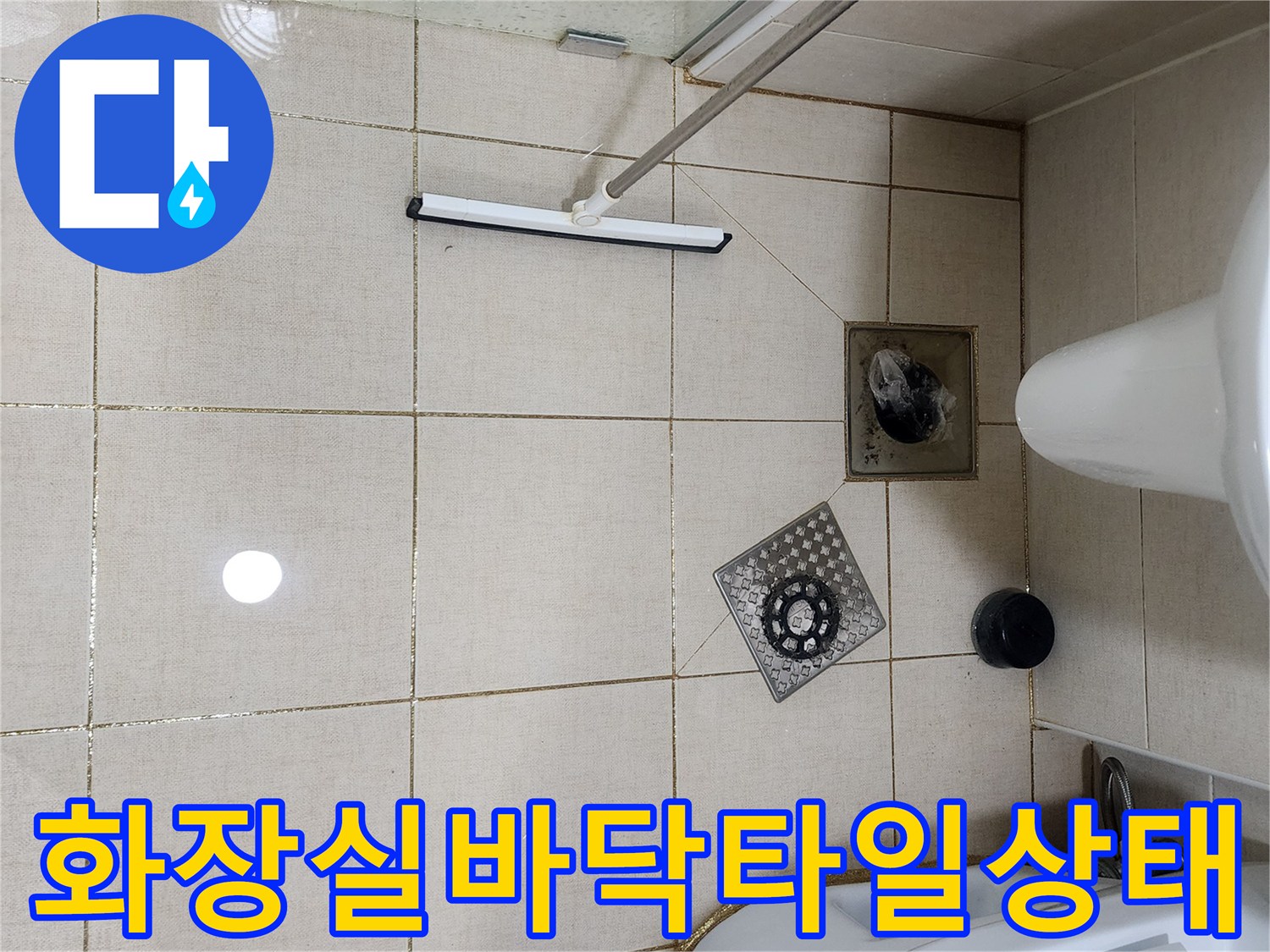 화장실 바닥의 타일과 유가 덮개가 찍힌 사진입니다.