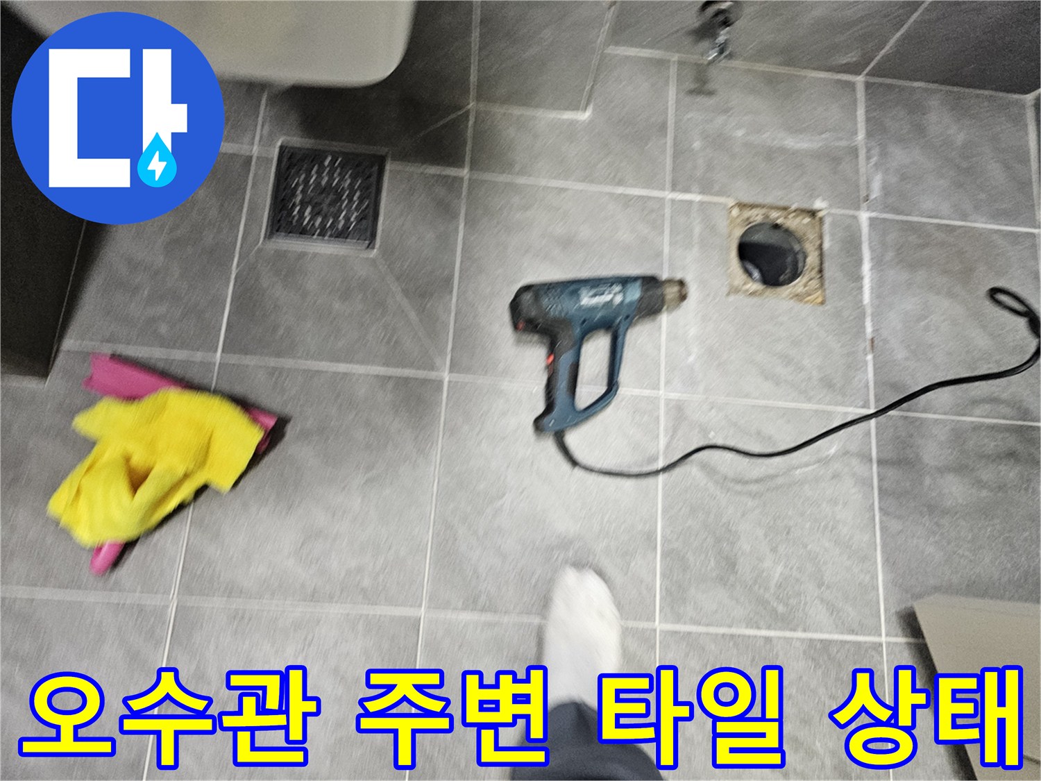 타일 바닥에 노출된 배관 입구와 작업 도구