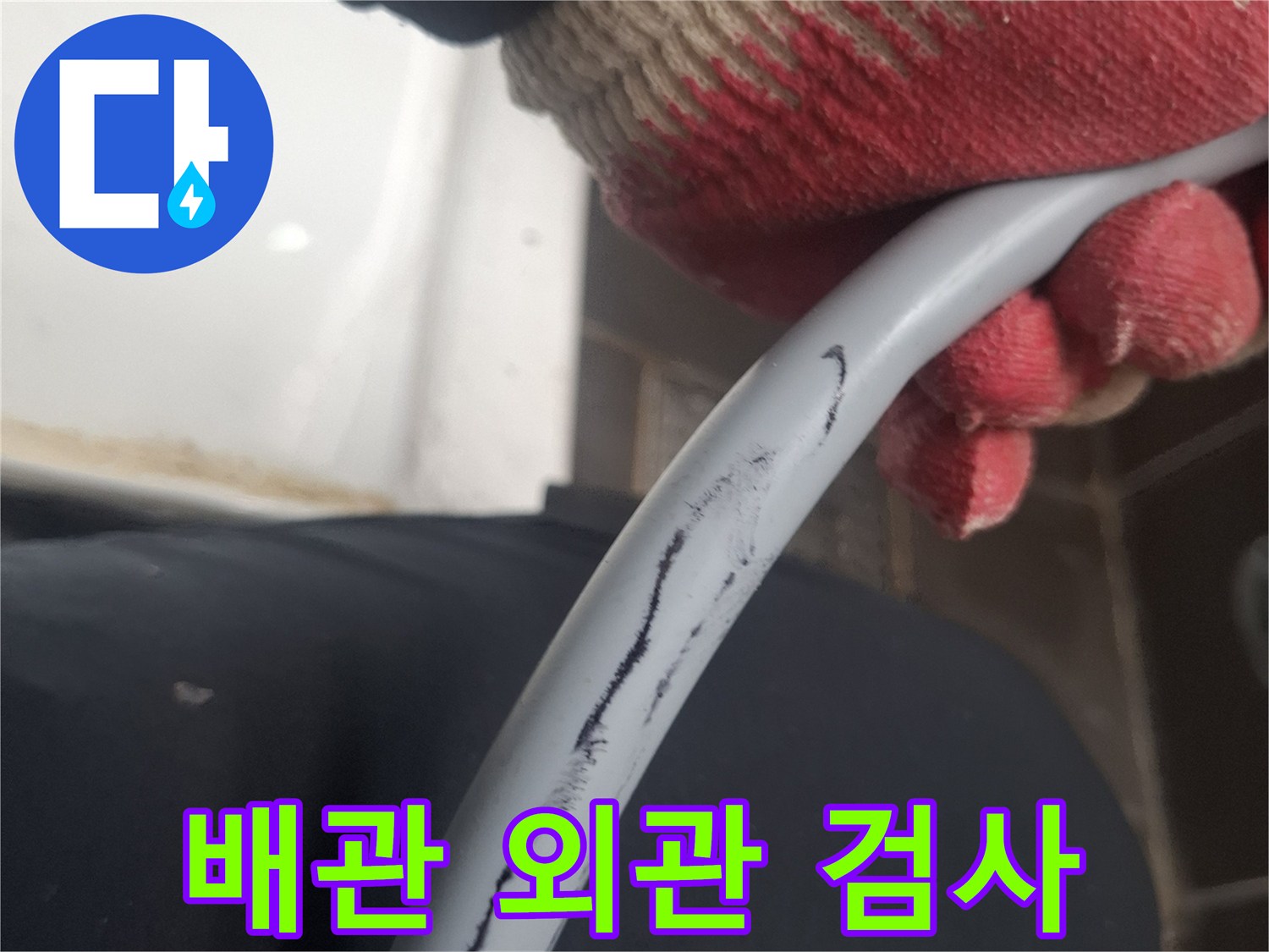 회색 배관을 손으로 잡고 살피는 현장 사진