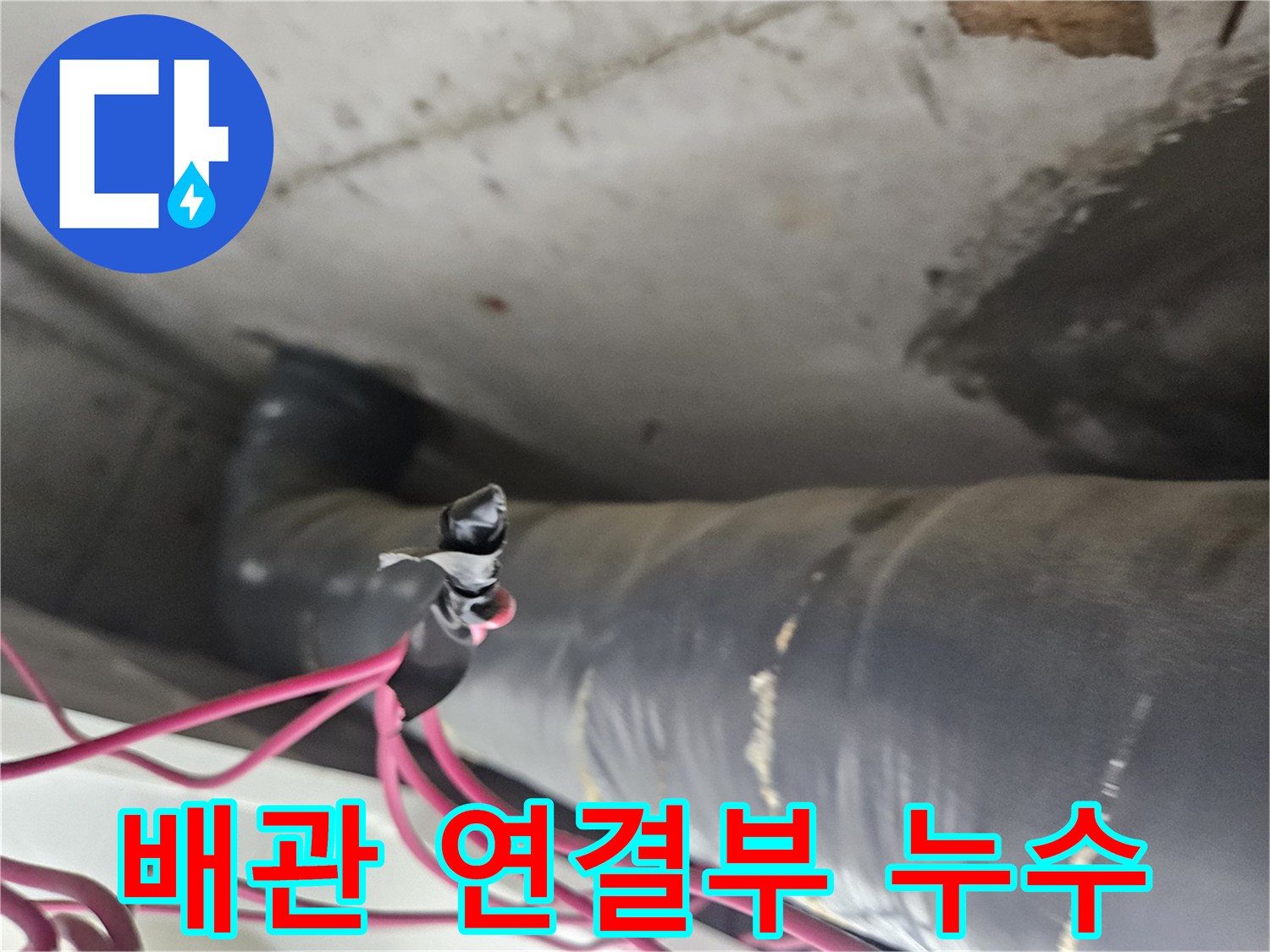 분홍색 전선이 지나가는 굵은 배관의 습기 찬 모습