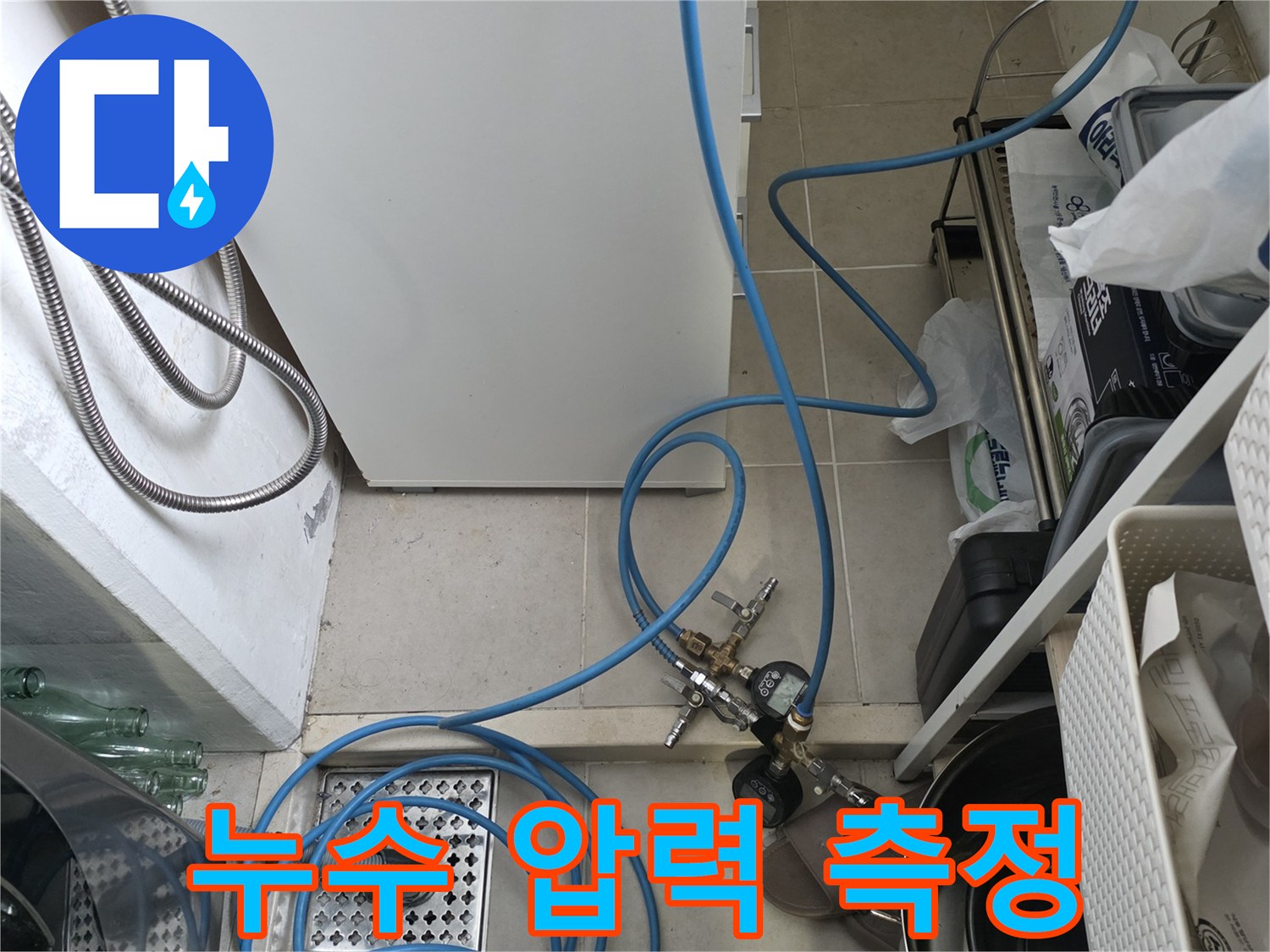 싱크대 배수구 근처에 설치된 파란색 호스와 측정 장치 연결 부위