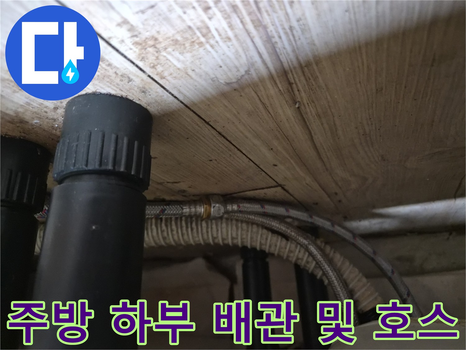 싱크대 아래쪽 공간에 보이는 검은색 PVC 배관과 은색 연자선 호스