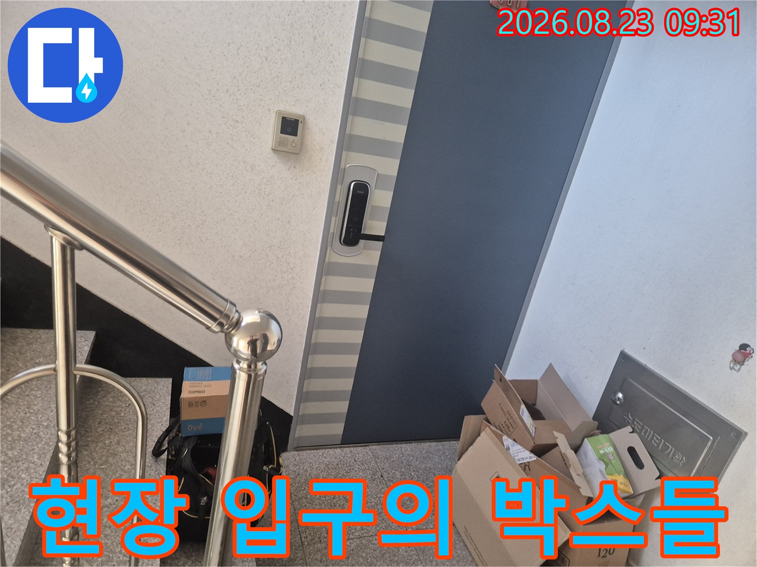 작업 자재 상자가 놓인 현관문 앞 복도 전경