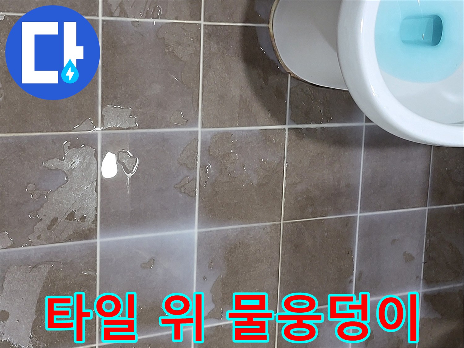 변기 근처 갈색 타일 위에 맺힌 물기 흔적
