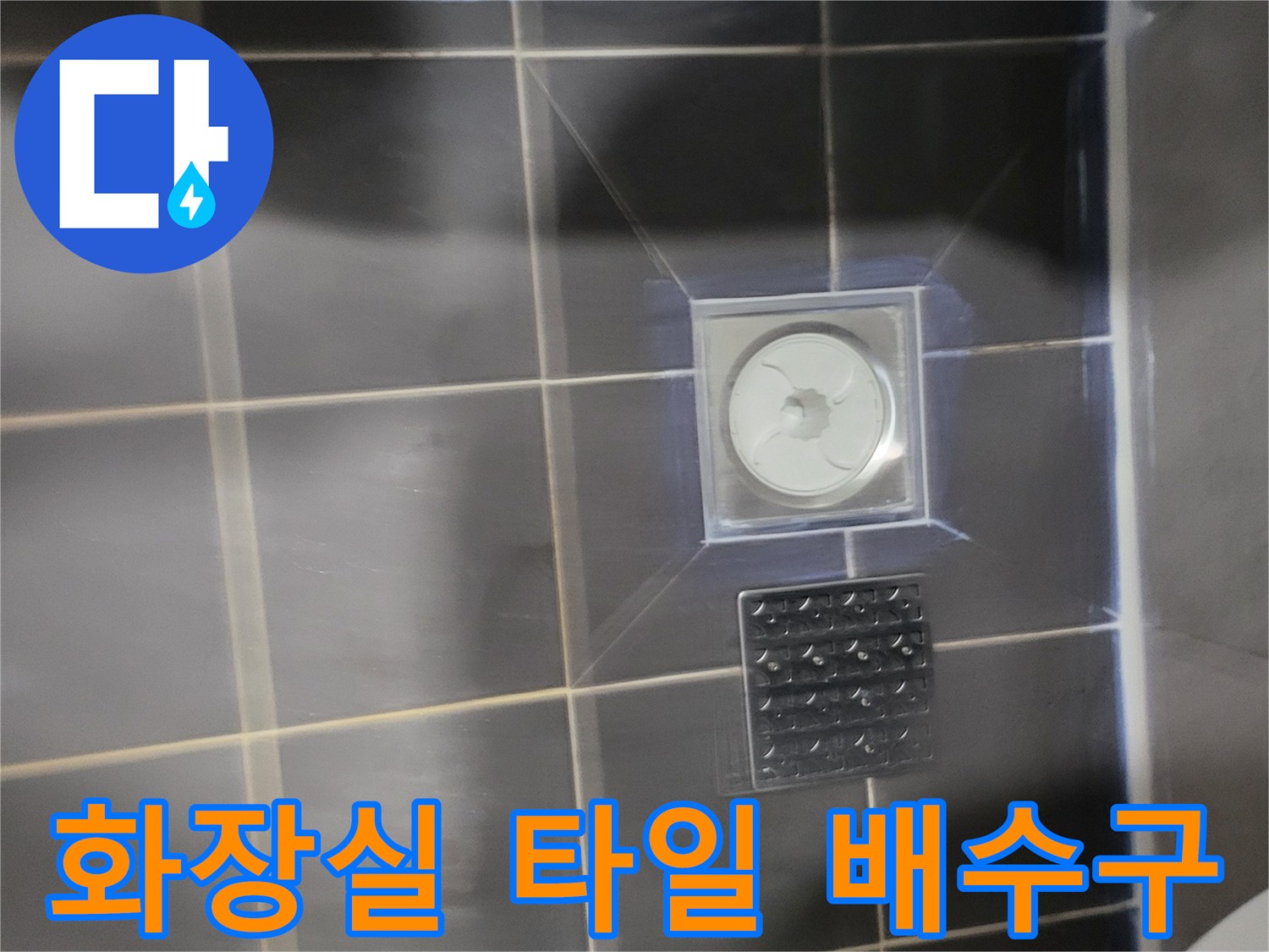 어두운 회색 타일과 덮개가 있는 배수구