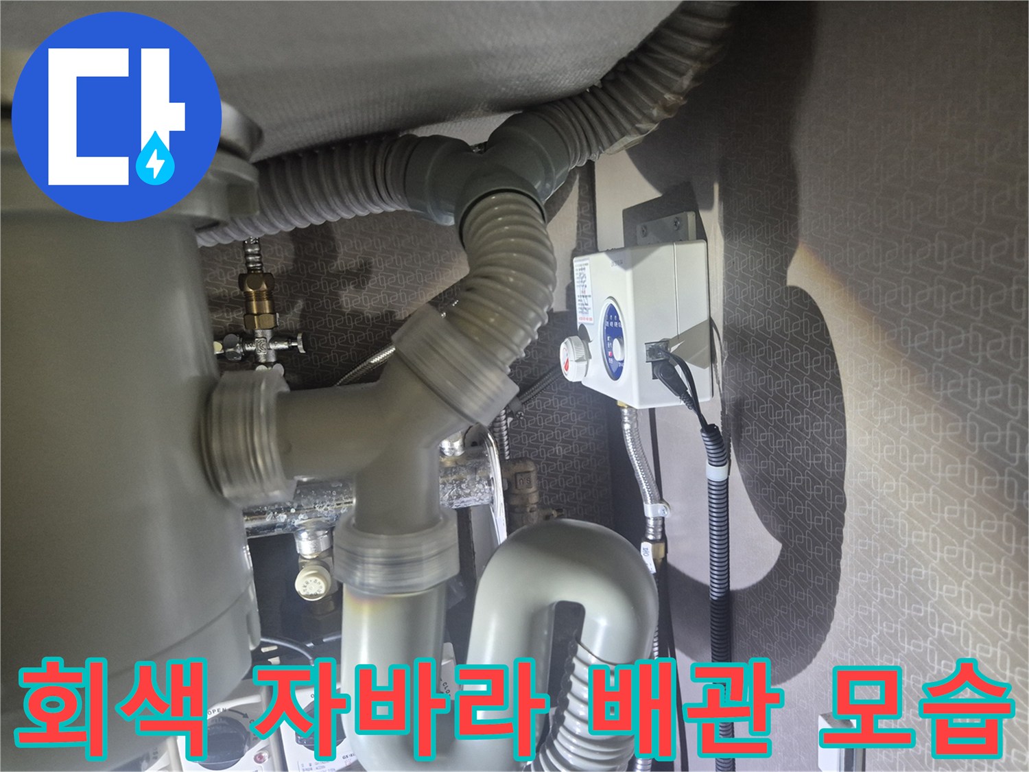 싱크대 아래쪽의 굴곡진 회색 배수 호스 연결 부위 촬영
