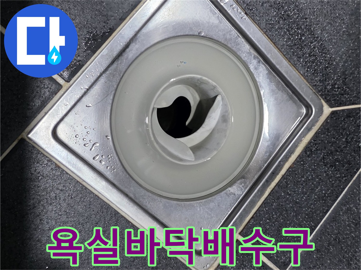 검은색 타일 바닥에 설치된 은색 배수구 덮개
