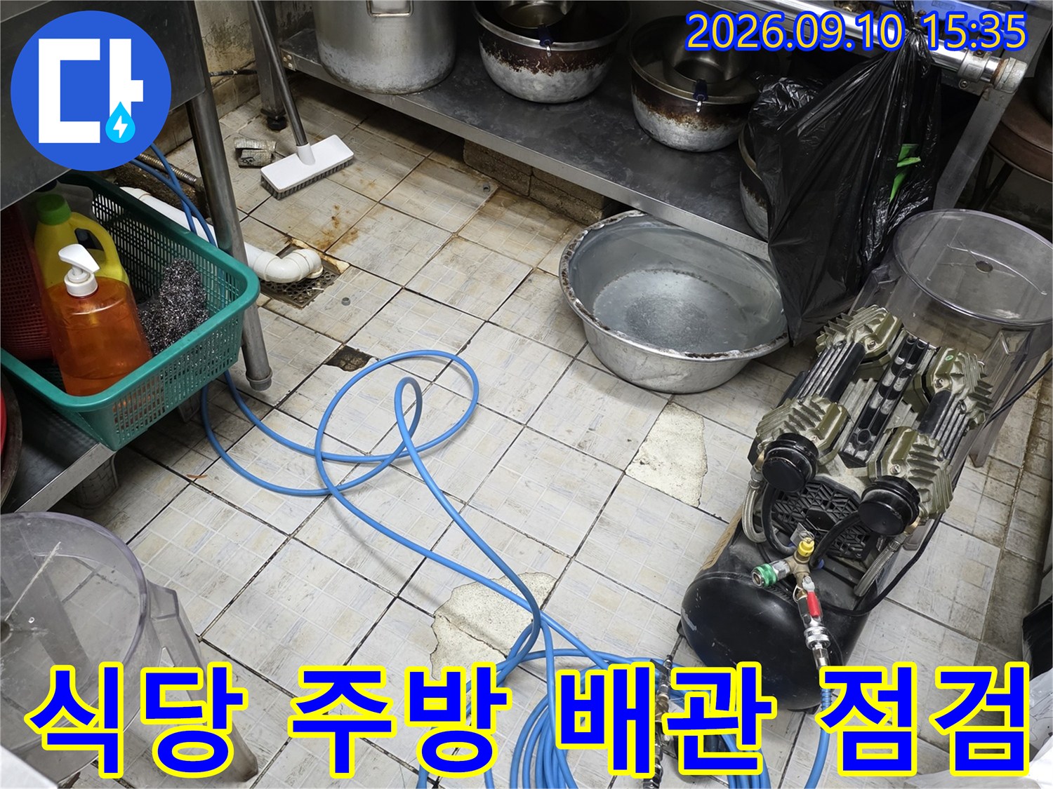 식당 주방 바닥에 놓인 공압 테스트 장비와 파란색 호스