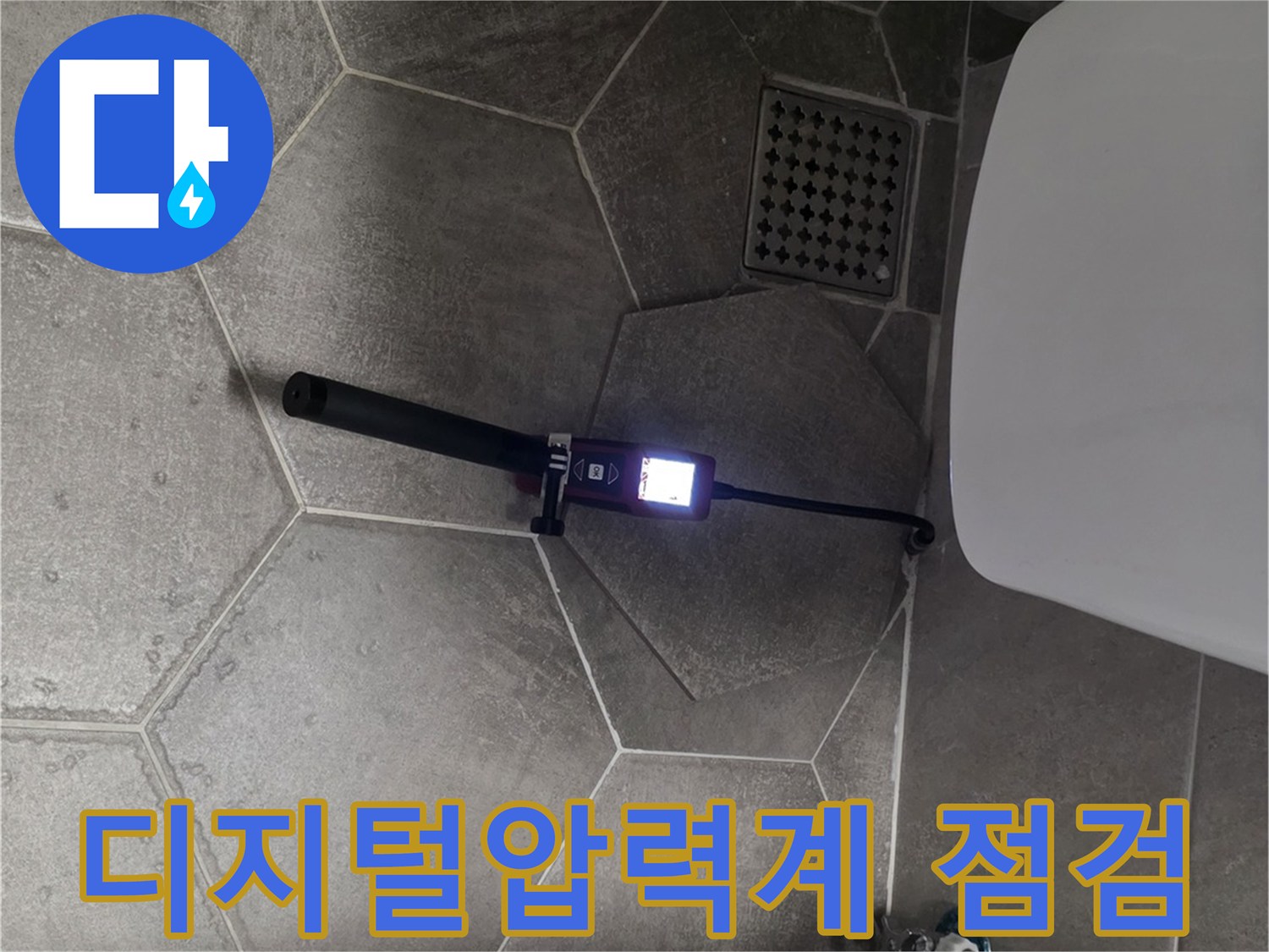 화장실 바닥에 설치된 디지털 압력계를 이용한 배관 기밀 테스트 중